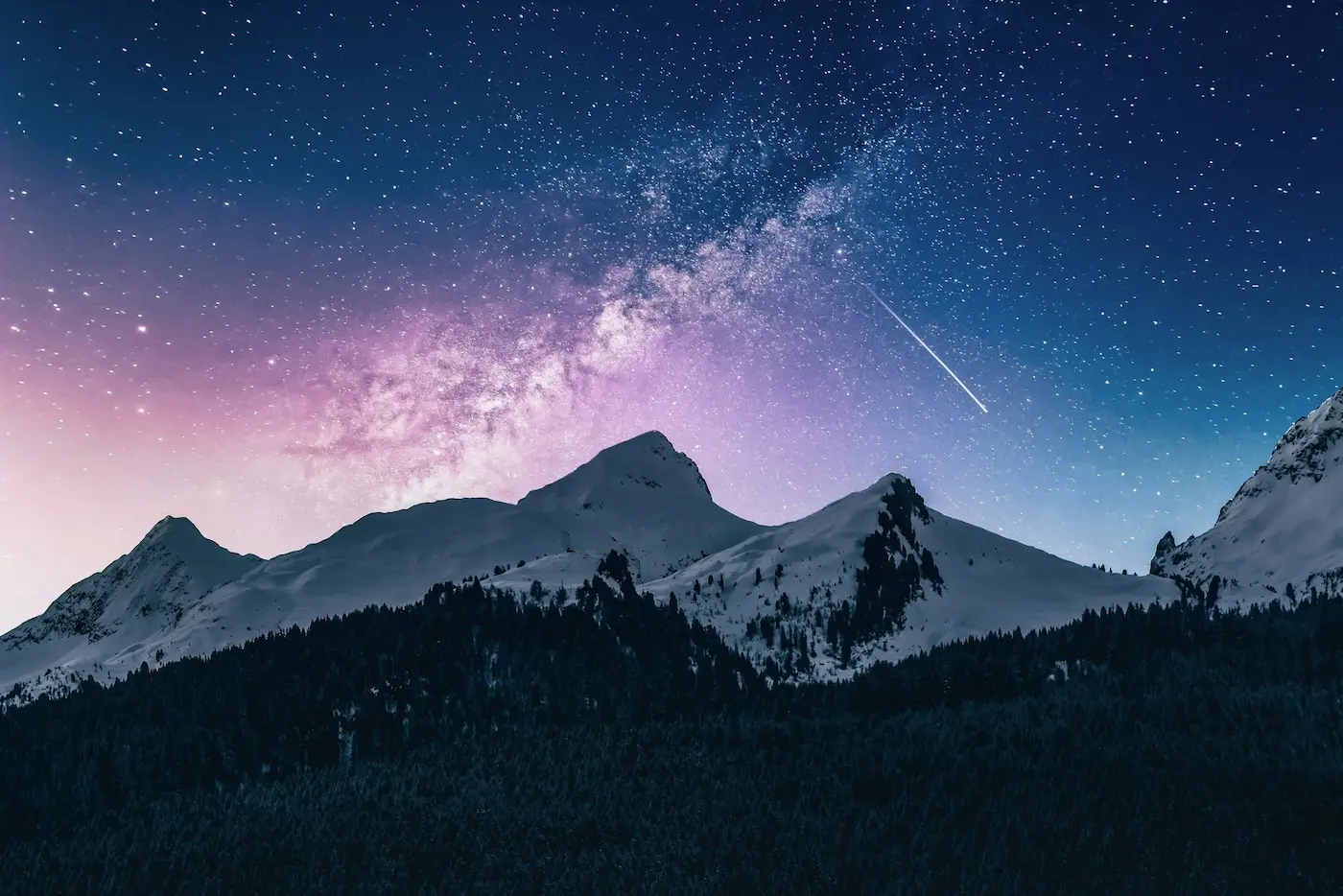 Snow-covered mountain silhouette under a starry night sky.
